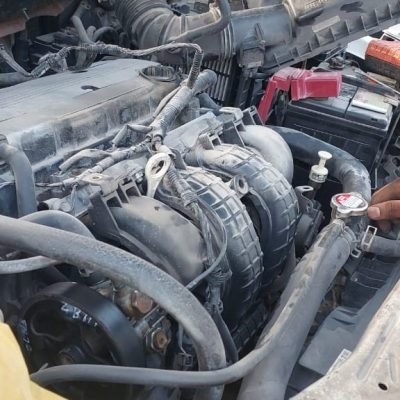 Mechanic inspecting car AC system components in Dubai workshop